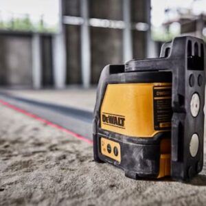 Лазерен нивелир DeWALT DW088K-XJ в действие на строителна площадка, показващ прецизността на прожектиране на червени лазерни линии върху бетонен под.