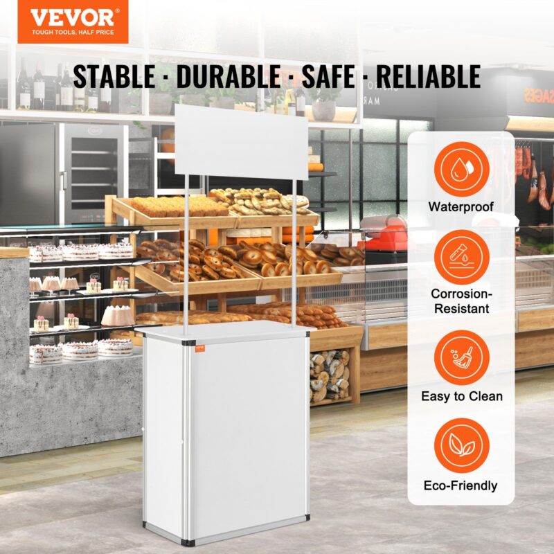 Бяла изложбена щанд маса VEVOR, поставена в пекарна. Надпис „Stable • Durable • Safe • Reliable“ с икони подчертаващи характеристиките: водоустойчивост, устойчивост на корозия, лесно почистване и екологичност.