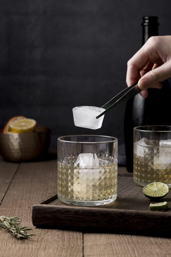close up man putting ice cube glass